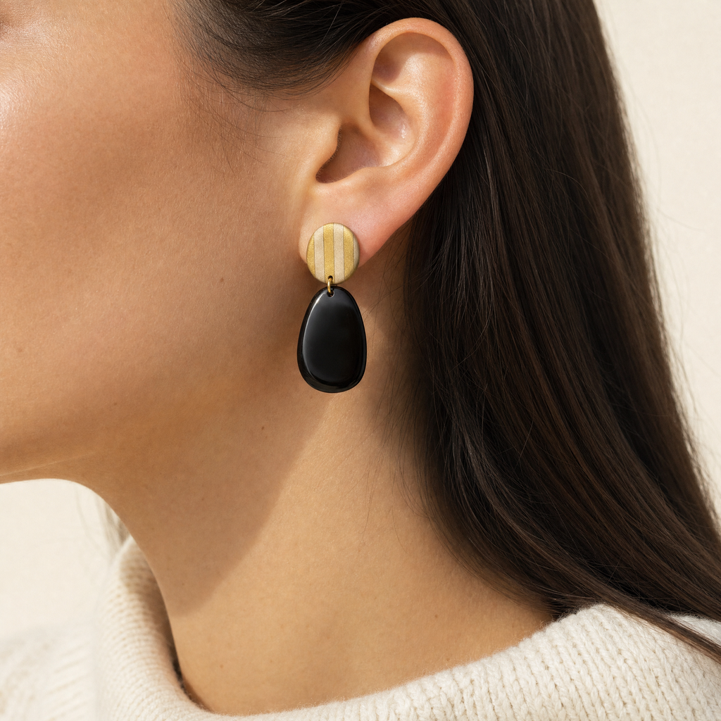Mujer usando los aros Ibiza Black de PINNA, aros colgantes livianos de 7 cm de largo