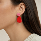 Mujer usando los aros Ibiza Red de PINNA, aros colgantes livianos de 7 cm de largo
