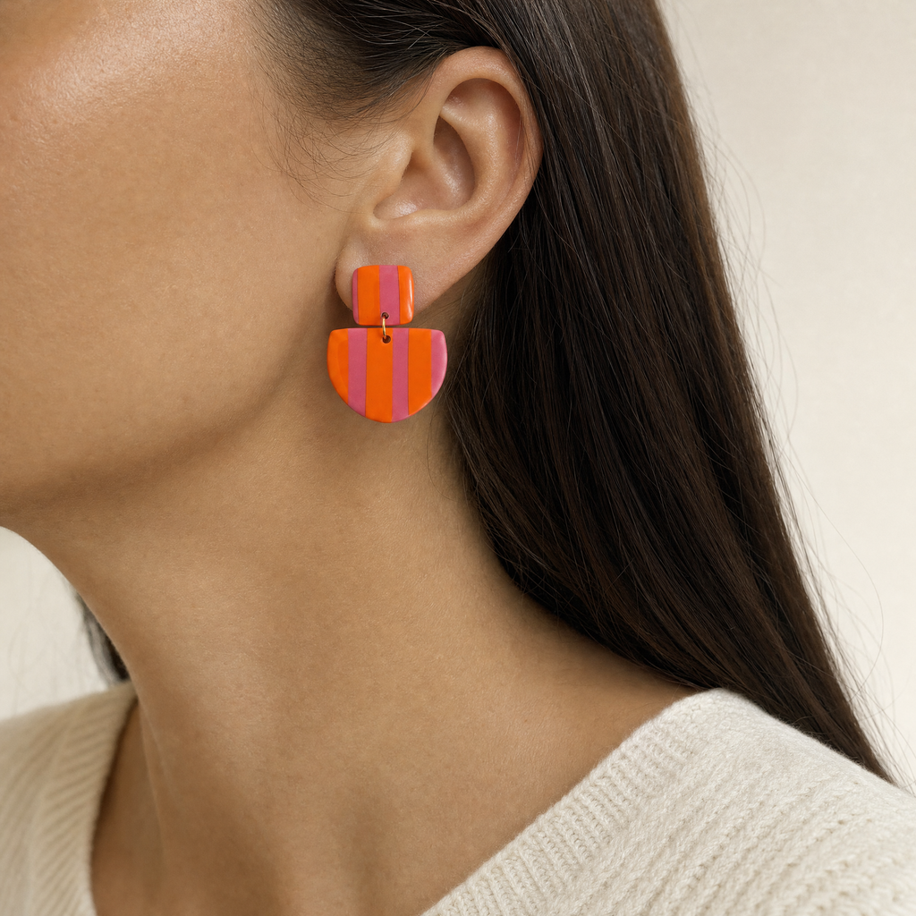 Mujer usando los aros Málaga Guayaba & Orange de PINNA, aros colgantes livianos de 6 cm de largo